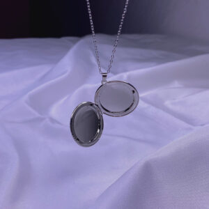 گردنبند قاب عکس دایره‌ای مدل NK-67 ترکیبی از طراحی ساده و احساس عمیق است. این گردنبند با قاب دایره‌ای نقره‌ای‌رنگ و زنجیر استیل ثابت، برای کسانی ساخته شده که خاطراتشان را همیشه با خود همراه دارند. طراحی بازشونده آن، فضای کوچکی برای قرار دادن عکس عزیزانت دارد، بی‌آنکه از ظرافت یا زیبایی ظاهری آن کم کند.